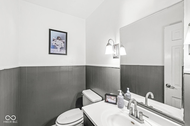 bathroom featuring vanity, toilet, and wooden walls