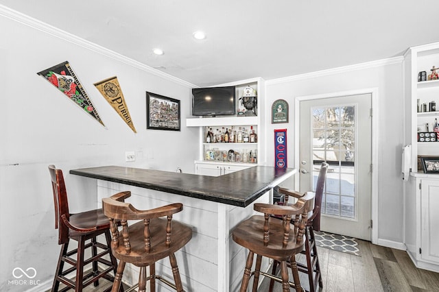 bar featuring ornamental molding, white cabinetry, and wood-type flooring