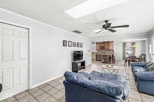 tiled living room featuring ceiling fan with notable chandelier, a skylight, and ornamental molding