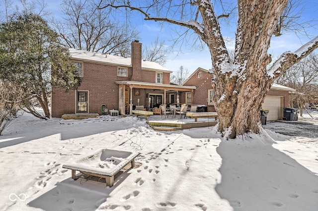 snow covered back of property featuring a garage