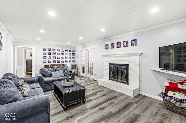 living room with hardwood / wood-style flooring, french doors, a textured ceiling, crown molding, and a fireplace