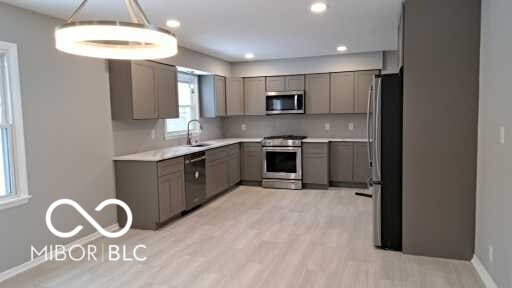 kitchen with appliances with stainless steel finishes, light hardwood / wood-style flooring, tasteful backsplash, gray cabinets, and sink