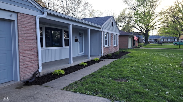 3121 W 13th St, Anderson, IN 46011 - property entrance with covered porch, brick siding, a yard, and roof with shingles
