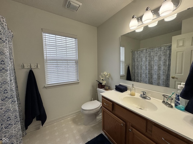 bathroom featuring a textured ceiling, vanity, and toilet