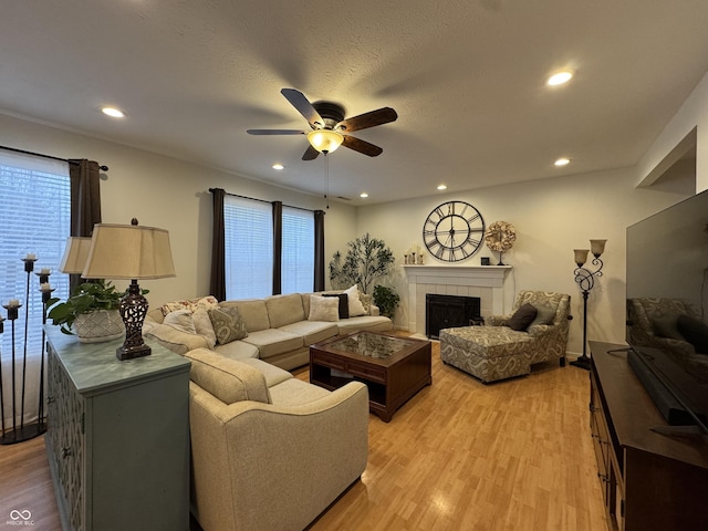 living room with ceiling fan, a tile fireplace, plenty of natural light, and light hardwood / wood-style floors