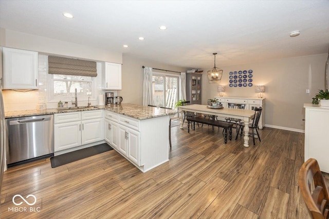 kitchen with dishwasher, a peninsula, dark wood-style floors, white cabinetry, and a sink