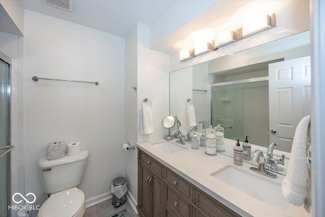 bathroom with toilet, visible vents, a tile shower, and a sink