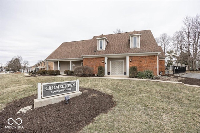 view of front of property featuring brick siding, a shingled roof, and a front lawn