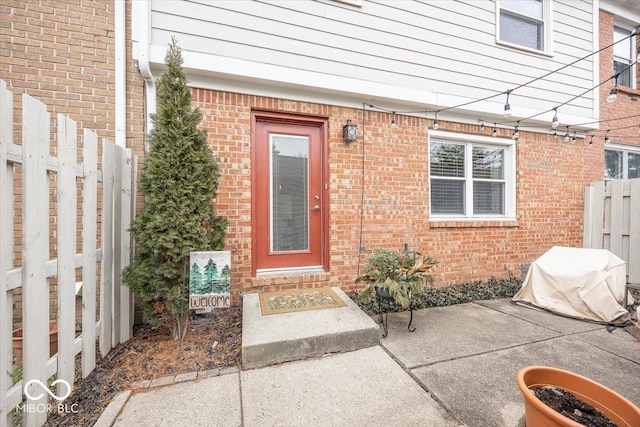 entrance to property with fence and brick siding