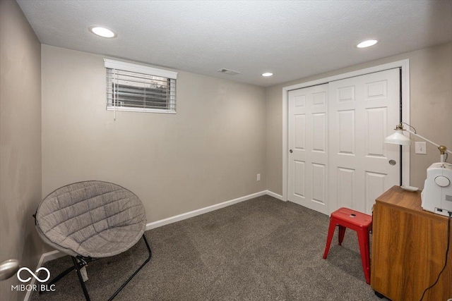 living area with a textured ceiling, baseboards, and dark colored carpet