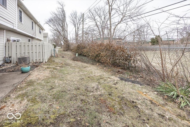 view of yard with central air condition unit and fence