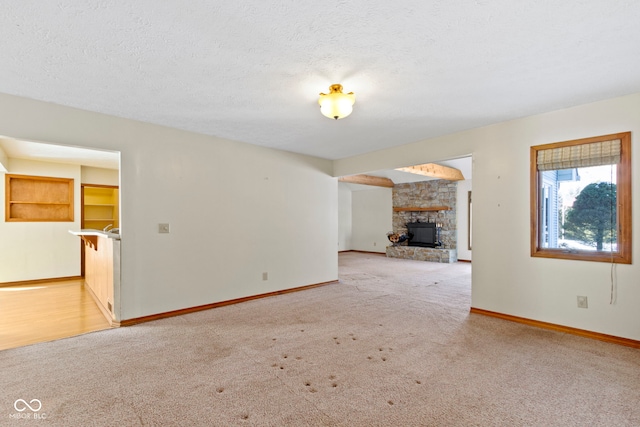 unfurnished living room featuring a fireplace, light carpet, and a textured ceiling