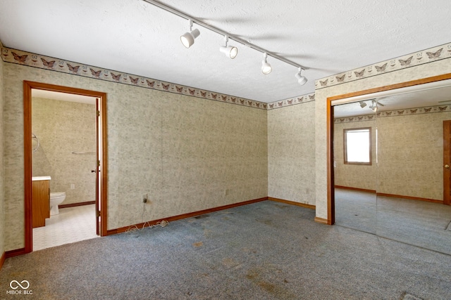 unfurnished room featuring rail lighting, carpet floors, and a textured ceiling