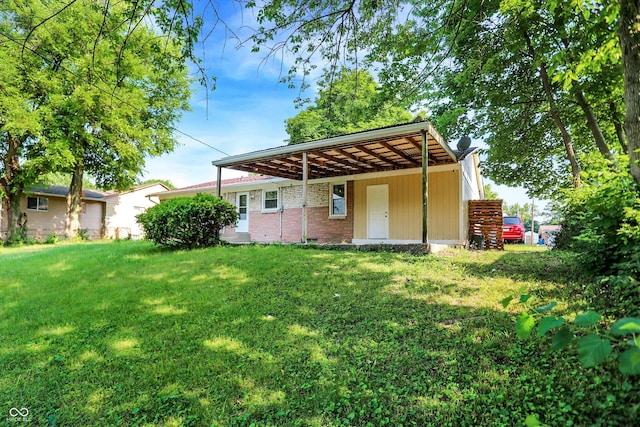 rear view of property featuring a carport and a lawn