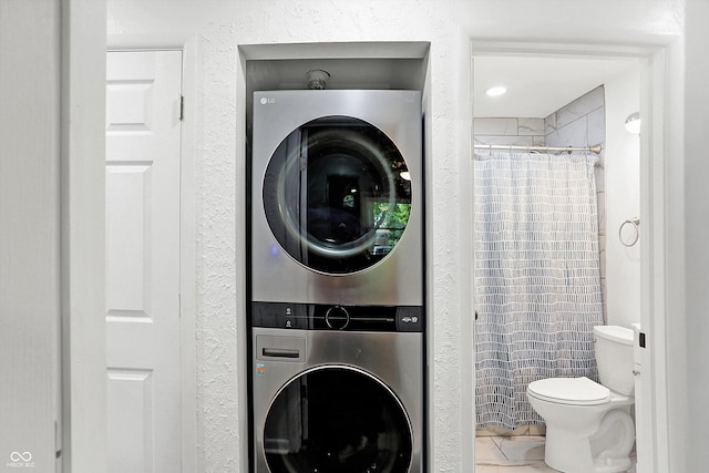 bathroom featuring stacked washer and clothes dryer, a shower with shower curtain, and toilet