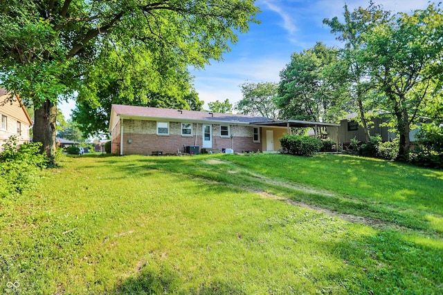 back of property with central AC unit and a yard