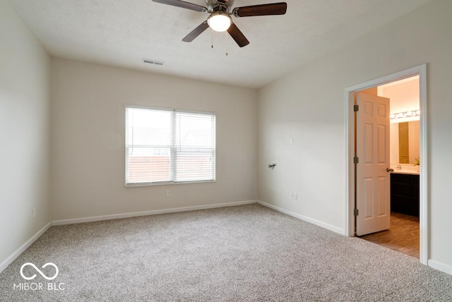 unfurnished bedroom featuring baseboards, ceiling fan, visible vents, and light colored carpet