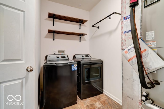 laundry room with laundry area, water heater, baseboards, and washing machine and clothes dryer