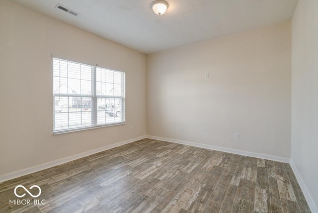 spare room featuring wood finished floors, visible vents, and baseboards