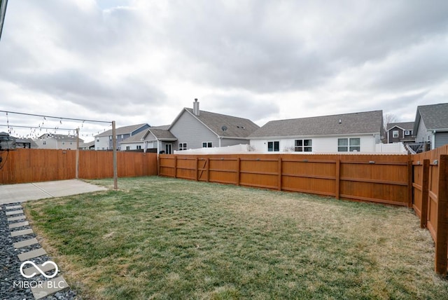 view of yard featuring a patio area, a fenced backyard, and a residential view