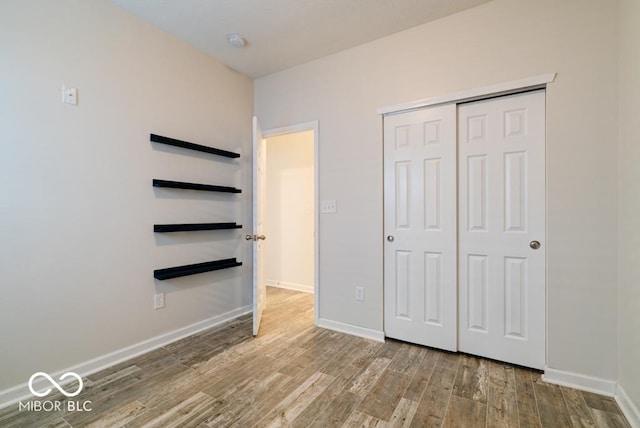 unfurnished bedroom with light wood-type flooring, baseboards, and a closet