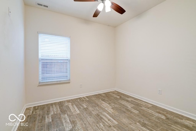 spare room with a ceiling fan, baseboards, visible vents, and wood finished floors