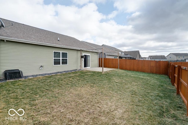 rear view of house with a yard, a fenced backyard, roof with shingles, and a patio