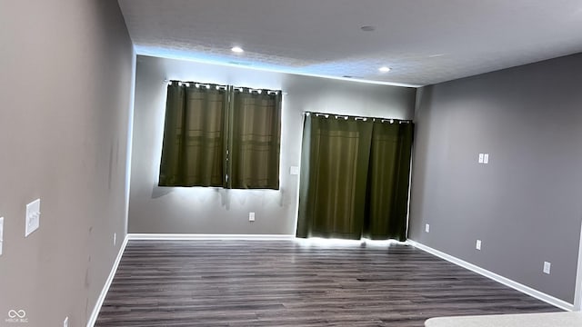 spare room with dark wood-type flooring, recessed lighting, a textured ceiling, and baseboards