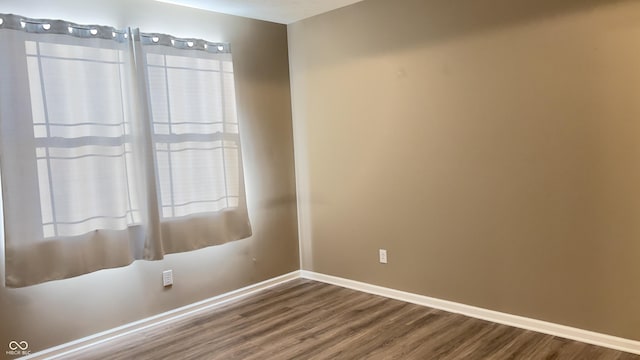 spare room with baseboards and wood finished floors