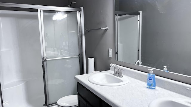 bathroom featuring a sink, a shower stall, toilet, and double vanity