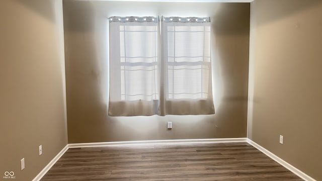 unfurnished room featuring dark wood-style floors, plenty of natural light, and baseboards