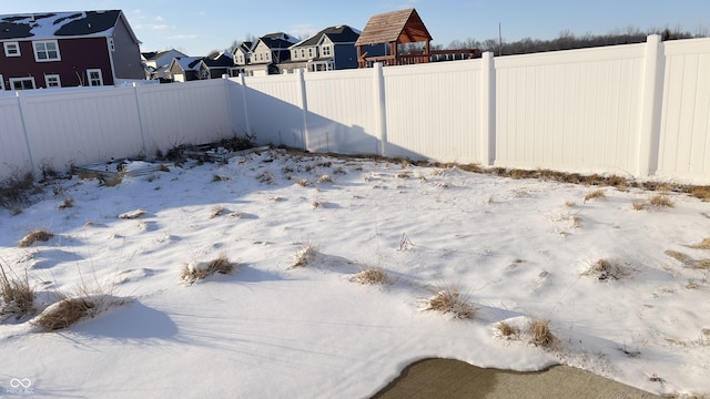 yard layered in snow with a fenced backyard and a residential view