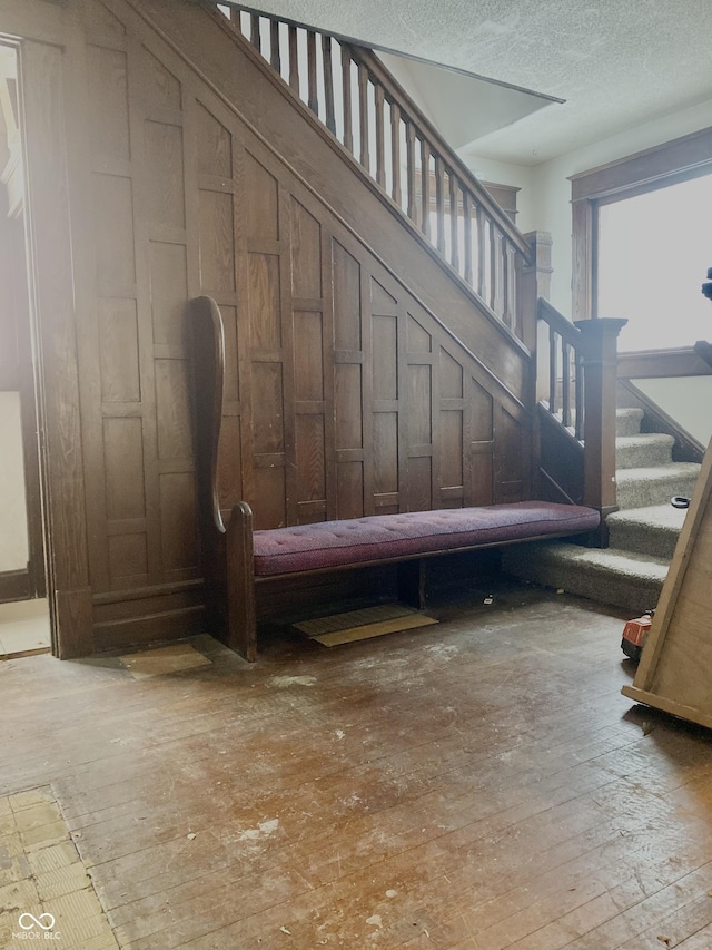 stairs featuring a textured ceiling and hardwood / wood-style floors