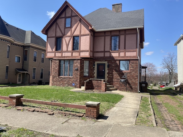 600 N Meridian St, Brazil, IN 47834 - tudor home with a chimney, brick siding, a front yard, a shingled roof, and stucco siding