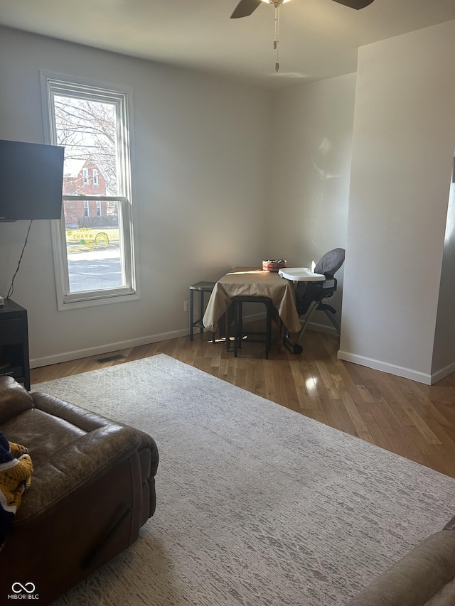 interior space with wood finished floors, a ceiling fan, and baseboards