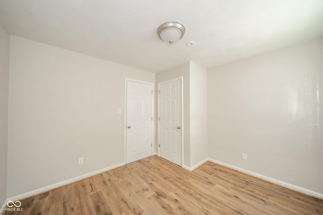 spare room featuring light wood-type flooring and baseboards