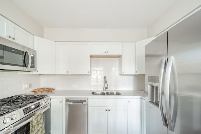 kitchen with a sink, stainless steel appliances, light countertops, and white cabinetry