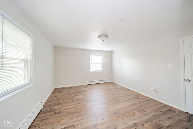 empty room featuring a baseboard radiator, baseboards, and wood finished floors