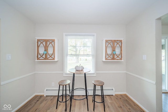 dining area with light wood finished floors, baseboards, and a baseboard heating unit