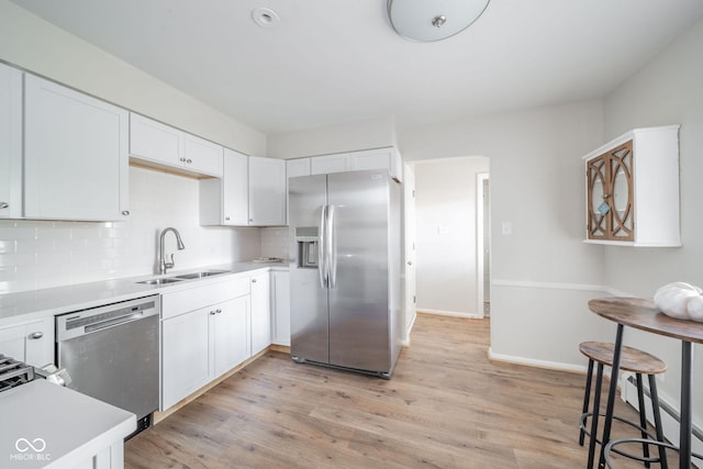 kitchen featuring light countertops, appliances with stainless steel finishes, a sink, and white cabinets