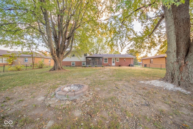 view of yard with a sunroom, a fenced backyard, and a fire pit