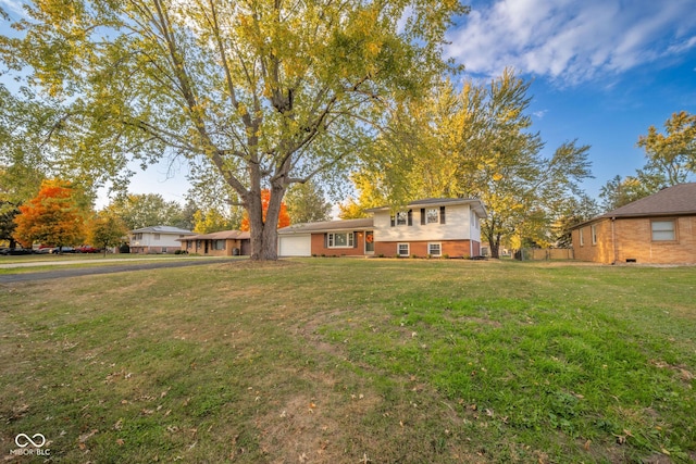 split level home featuring a garage, a front lawn, and brick siding