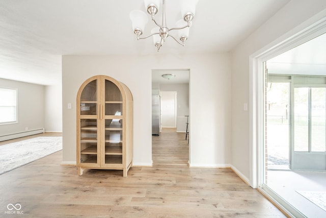 unfurnished dining area with light wood-type flooring, a baseboard heating unit, baseboards, and a notable chandelier