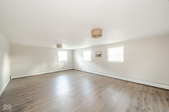 empty room featuring baseboard heating and wood finished floors