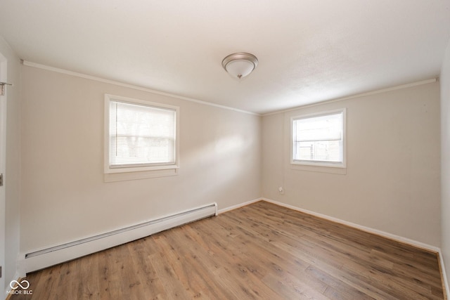 spare room with a baseboard heating unit, crown molding, baseboards, and wood finished floors