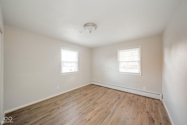 unfurnished room featuring light wood-type flooring, a baseboard radiator, and baseboards