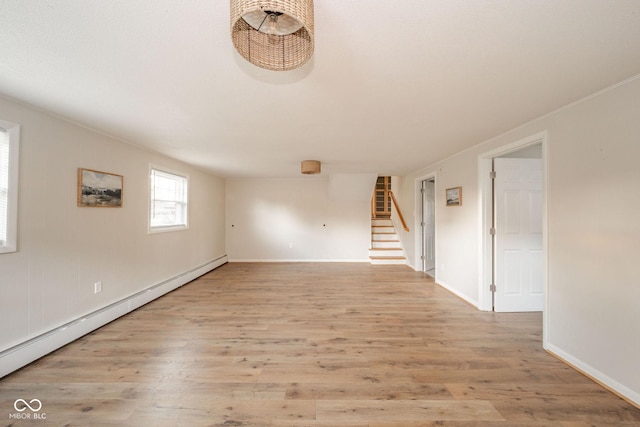 empty room with baseboards, light wood-style flooring, baseboard heating, and stairs