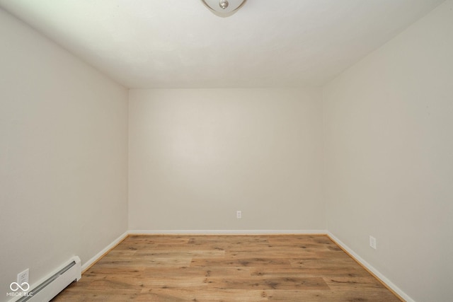 spare room featuring light wood-type flooring, baseboards, and a baseboard heating unit