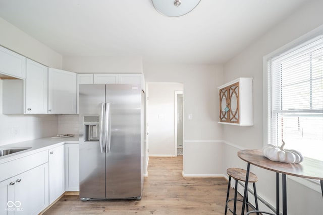 kitchen featuring light countertops, white cabinetry, stainless steel refrigerator with ice dispenser, and light wood finished floors