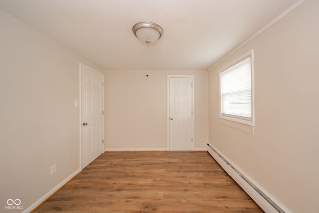 empty room featuring baseboards, baseboard heating, and wood finished floors